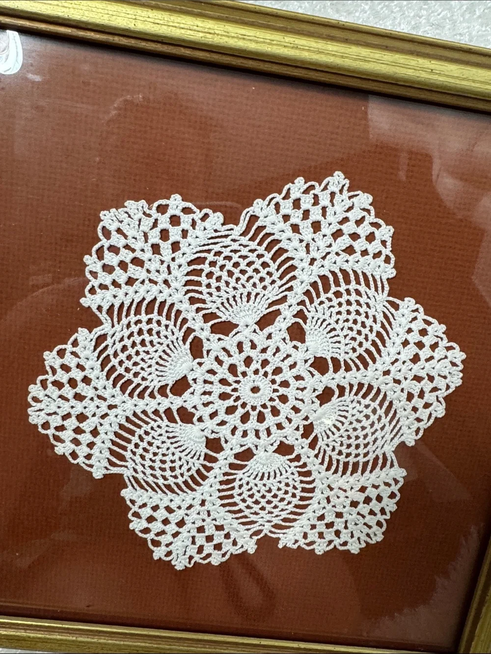 Framed doily in gold frame